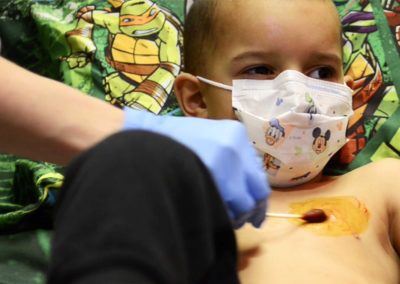 A nurse prepares Tae's port, a small disc that sits just under the skin, so that he can receive the chemotherapy drugs.