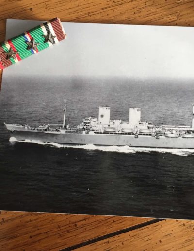 The USS General W. H. Gordon, the troop transport ship that took Walter Auxter to Cherbourg, France, next to his ribbon bars with stars from WWII.